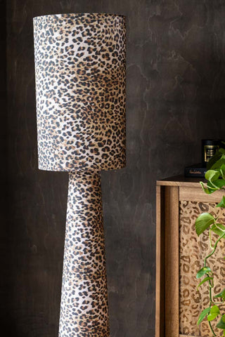 Close-up of the Leopard Love Print Floor Lamp, next to a wooden leopard print sideboard with a plant and accessories on.