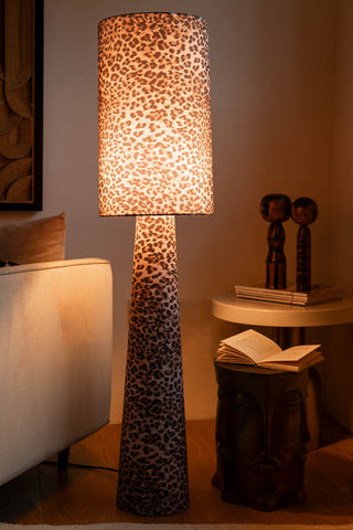 The Leopard Love Print Floor Lamp switched on and displayed next to a sofa and side table with various accessories.