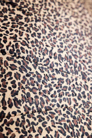 A heavy duty umbrella in leopard print. The image shows the detail of water droplets on the outside that makes this umbrella waterproof.