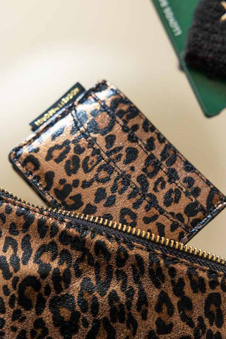 The Leopard Print Card Holder displayed on a surface with some other accessories.