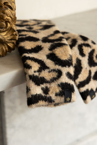 The Leopard Print Handwarmers displayed on a shelf next to a decorative gold frame.