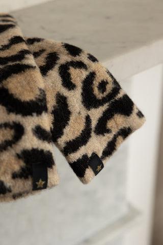 Detail shot of the Leopard Print Handwarmers displayed on the edge of a shelf.