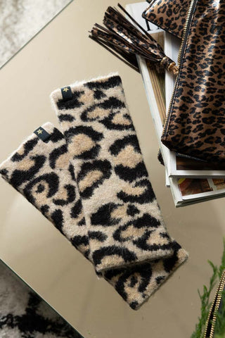 The Leopard Print Handwarmers styled on a table with some magazines, greenery, and a leopard print bag/card holder.