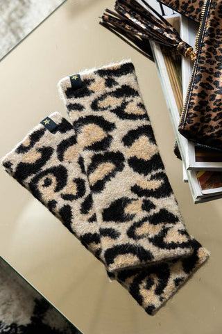 The Leopard Print Handwarmers displayed on a table with a leopard print clutch bag and card holder, with some magazines.