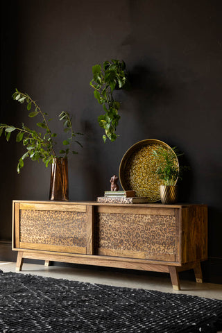 Leopard TV Unit styled with a tray, vase, books, ornament and plants in front of a dark wall.