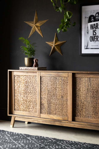 The Leopard Sideboard styled in front of a black wall with an art print, decorative stars and other home accessories.