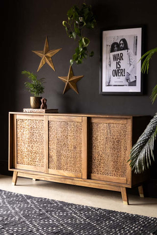 The Leopard Sideboard styled in front of a black wall with an art print, plants and various accessories.