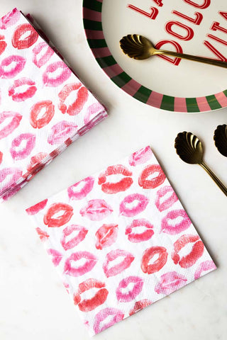 The Lips Napkins - Pack of 20 displayed on a table with a plate and some gold spoons.