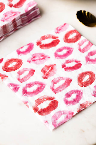 A Lips Napkin displayed on a white surface with a spoon, with a stack of napkins in the background.