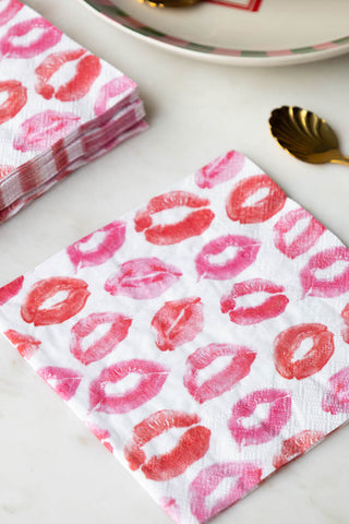 The Lips Napkins - Pack of 20 on a white surface with a plate and some spoons.