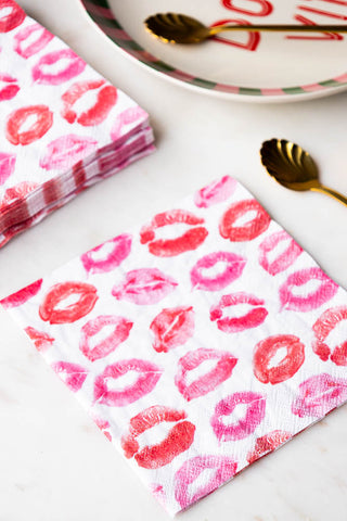 The Lips Napkins - Pack of 20 displayed on a table with gold spoons and a plate.