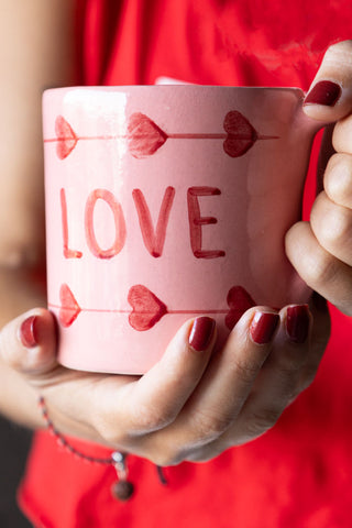 The Love Hand-Painted Cappuccino Mug being held in a model's hands.