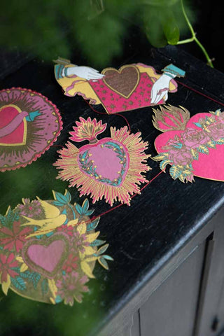 The Love Hearts Paper Garland laid down on the top of a black sideboard.