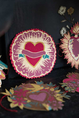 The Love Hearts Paper Garland laying down and leaning against a dark background.