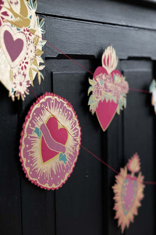 The Love Hearts Paper Garland displayed hanging in front of a black sideboard.