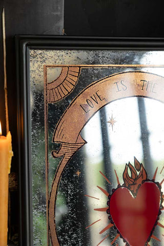 Close-up of one corner of the Love Is The Drug Decorative Mirror.