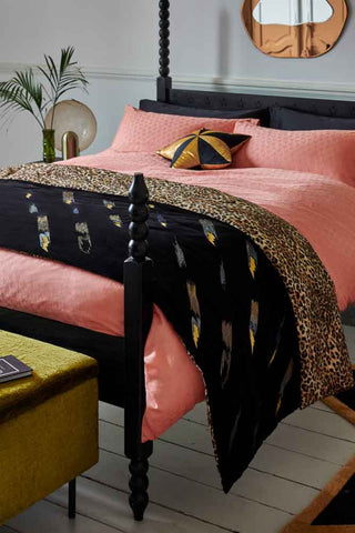 The Reversible Black Lovestruck & Leopard Print Throw styled folded across a bed.