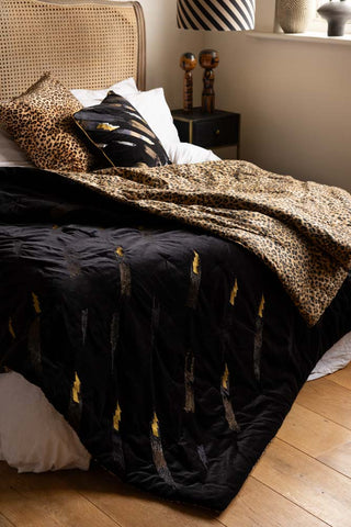 The Reversible Black Lovestruck & Leopard Print Throw draped across a bed.