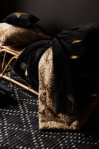 The Reversible Black Lovestruck & Leopard Print Throw draped across a wicker bench.