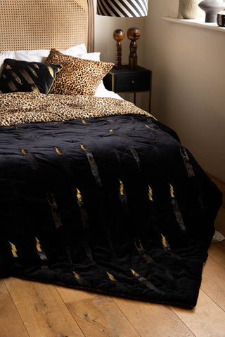 The Reversible Black Lovestruck & Leopard Print Throw styled on a bed with cushions.