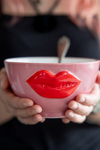 Whimsical pink ceramic bowl featuring a bold red lips design in 3D  held in two hands.