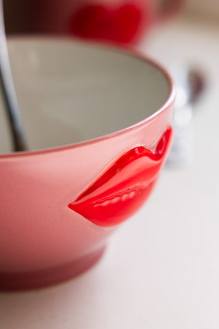 Chic pink bowl with a raised red lips detail, accompanied by a silver spoon, ideal for breakfast or snacks.