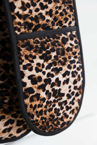 Close-up of the Luxury Leopard Print Oven Gloves hanging in front of a white background.