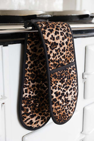 The Luxury Leopard Print Oven Gloves displayed on a rail on the front of an oven.