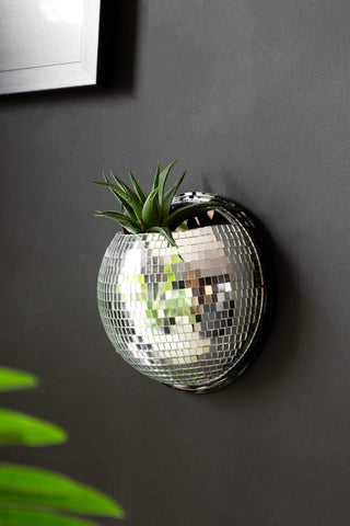 Silver disco mirror ball plant holder, with cactus plant inside, styled against a matt black wall 