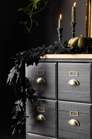 The Maple Leaf Garland draped across the corner of a black sideboard, styled with lit candles, a pumpkin and some greenery.