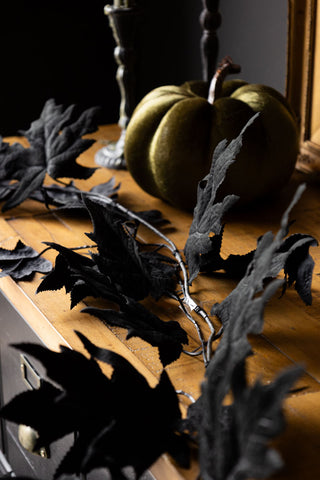 Close-up of the Maple Leaf Garland styled on a wooden and black sideboard with a pumpkin decoration and candlestick holders.