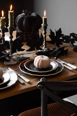 The Maple Leaf Garland styled across the centre of a Halloween tablescape with various tableware and lit candles.