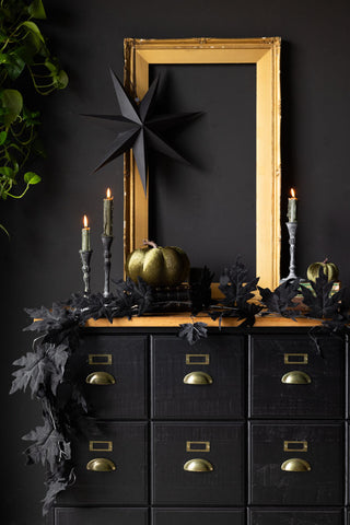 The Maple Leaf Garland draped across a sideboard, styled with a frame, various candles, Halloween decorations and greenery.