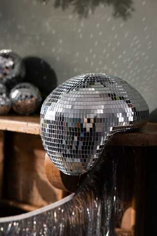 The Melty Disco Ball styled on a wooden mantlepiece.