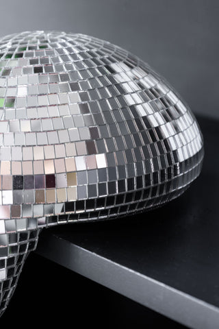 The edge of a silver disco mirror ball, styled on a black cabinet 