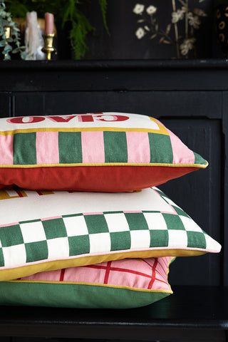 A stack of patterned cushions displayed in front of a black sideboard.