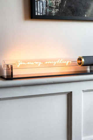 The Message In A Tube Light - You Are My Everything illuminated and displayed on a shelf by the wall, with an art print in the corner of the shot.