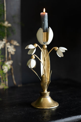 The Metal Floral Candle Holder displayed with a lit candle inside on a black sideboard.