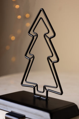 The Metal Tree Stocking Holder with lights in the background.