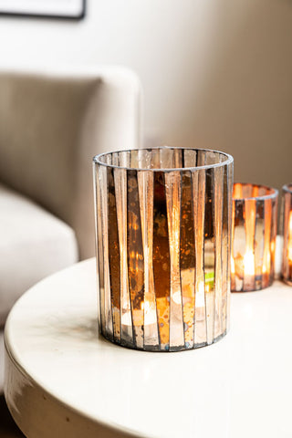 The Metallic Mosaic Effect Glass Candleholder on a table with smaller tealight holders in the background.