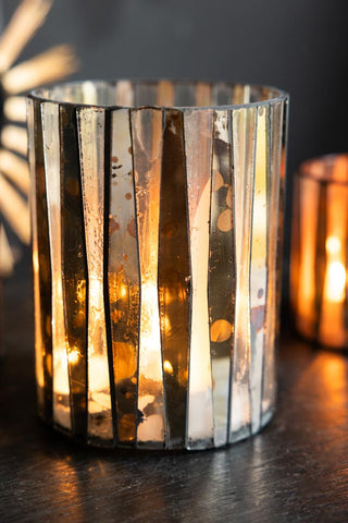 The Metallic Mosaic Effect Glass Candleholder with a lit candle inside.