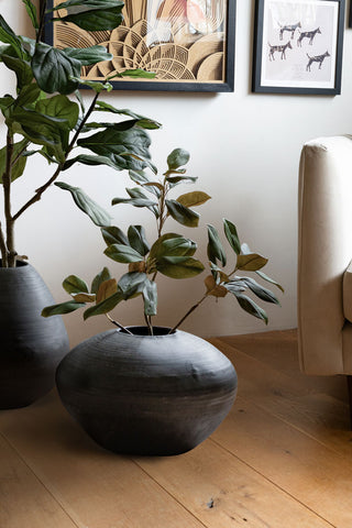 The Mexica Patterned Large Vase styled on the floor with a plant inside, next to another vase and a sofa.