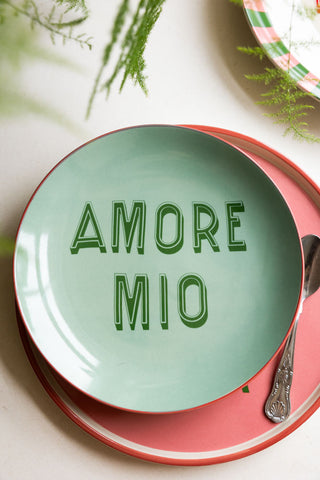 The Mint Green Amore Mio Plate styled on a pink plate with a spoon, with another plate and greenery also in the shot.