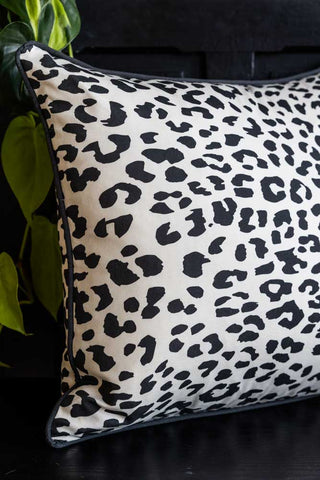 A closer cropped image of The Monochrome Leopard Cushion styled on a black bench