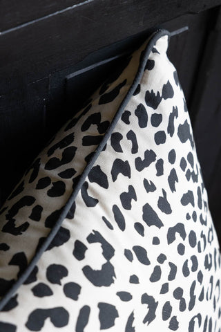 A detailed image of the piping on The Monochrome Leopard Cushion styled on a black bench