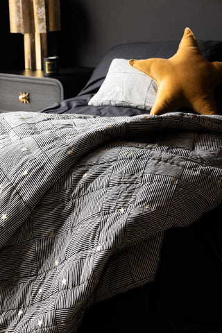 The Monochrome & Gold Star Detail Print Quilt in King-Size draped across the end of a bed.