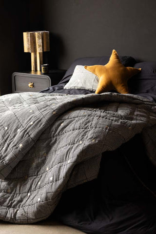 The Monochrome & Gold Star Detail Print Quilt in King-Size styled draped across a bed.