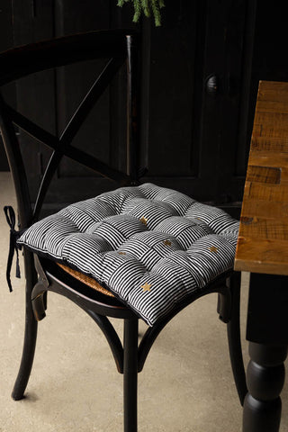 The Monochrome & Gold Star Detail Print Seat Cushion on a dining chair, styled next to a dining table.