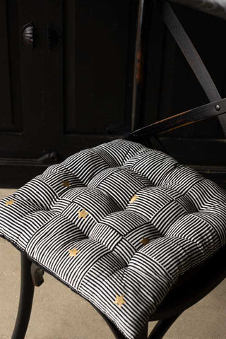 The Monochrome & Gold Star Detail Print Seat Cushion displayed on a dining chair.