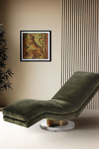 Beautiful moss green velvet chaise-like chair in a neutral living room. In the background quirky artwork is hung on the walls.